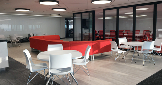 View of an office floor with tables, a large sofa and a meeting room